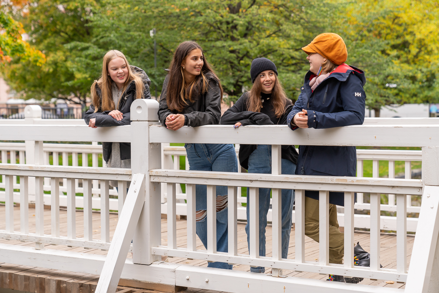 Neljä nuorta seisovat sillalla ja juttelevat.