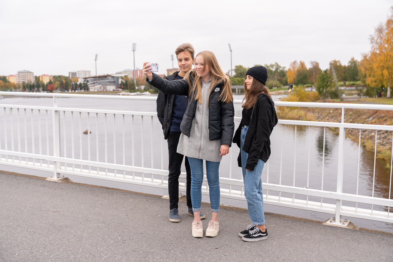 Kolme nuorta sillalla ottamassa yhteiskuvaa.