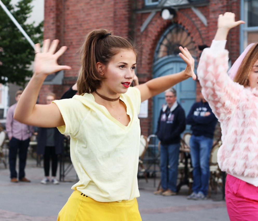Kaksi tyttöä tanssii Oulun kauppahallin edessä ja taustalla yleisöä katsomassa.